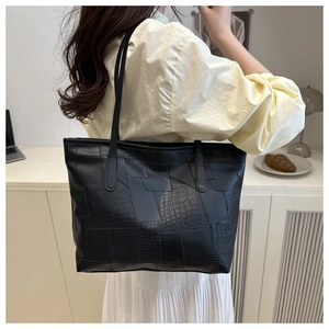 Detail of black tote bag featuring geometric patchwork and textured crocodile patterns