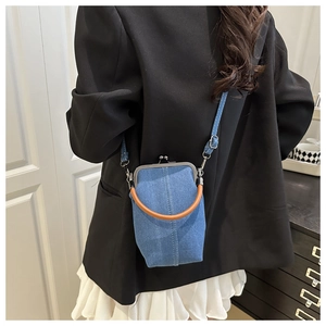 Detail of vintage denim kiss-lock bag featuring blue fabric and metal frame handle