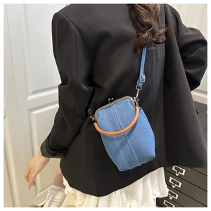 Detail of blue denim crossbody bag featuring a vintage metal clasp and leather handle