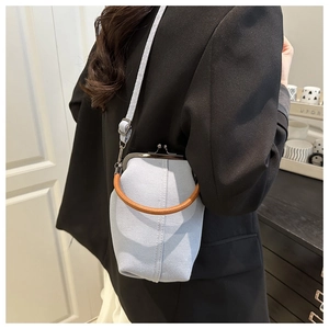 Detail of light blue denim crossbody bag with vintage frame closure and woven handle