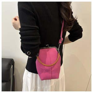 Detail of rose red canvas frame bag with round wooden handle and metal kiss-lock closure