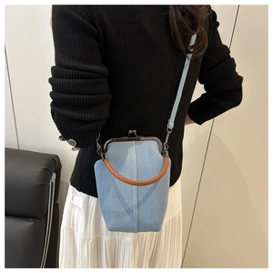 Detail of light blue denim crossbody bag with vintage gold clasp and brown round handle