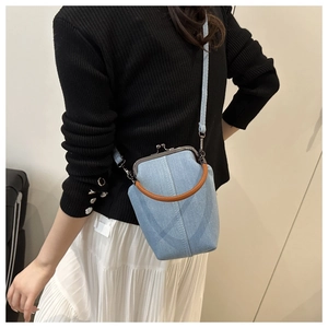 Blue denim mini kiss-lock bag shown on model with silver clasp and ring handle