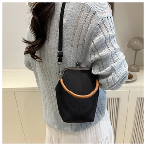 Close-up of vintage kiss lock closure and brown handle on black canvas crossbody bag
