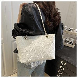 Close-up of white woven tweed tote bag with gold-tone chain strap on female model