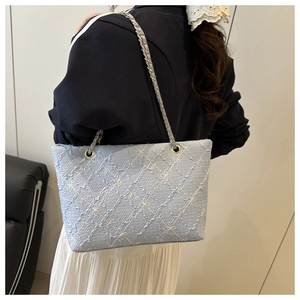 Close-up of light blue quilted embroidery tote bag with gold chain leather strap details