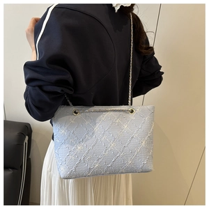 Detail of light blue tote bag with floral embroidery texture and gold chain strap