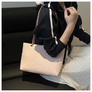 Dettaglio della borsa tote in tweed rosa con cuciture trapuntate e catena in metallo