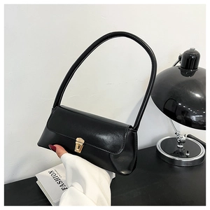 Detailed macro shot of a black glossy baguette bag with elegant golden metal buckle clasp