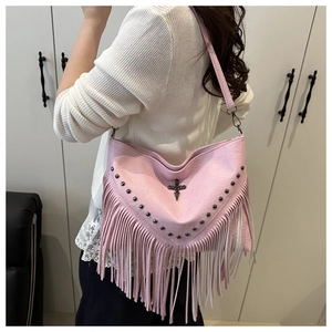 Detail of pink faux leather tote with metal studs, cross hardware and long fringe tassels