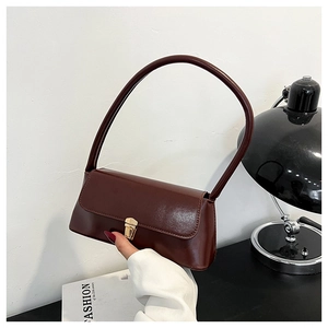 Macro detail of glossy red baguette bag with vintage gold square buckle and long handle