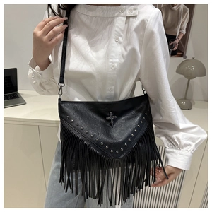 Close-up of black crossbody bag featuring silver rivets, metal cross, and long tassels