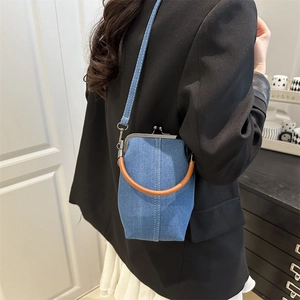 Blue denim bucket bag with retro metal clasp and brown ring handle worn by model