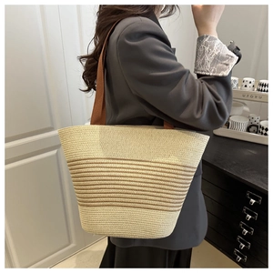 Detail of striped straw tote bag showing cream and brown woven texture and handles