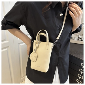 Mini sac seau blanc crème avec pendentif chien, porté par un mannequin en intérieur chic