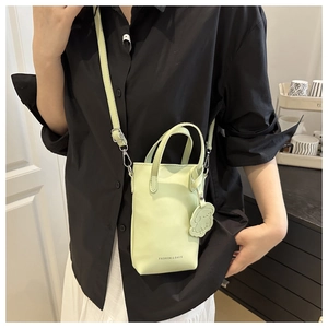 Detail of light green pebble leather mini bucket bag with fashion text and dog charm
