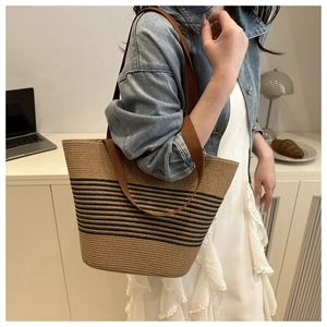Close-up of woven tote bag with black stripes and brown straps in a lifestyle setting
