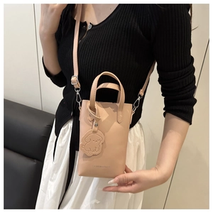 Close-up of pink bucket bag with dog charm and detachable strap for fashion styling