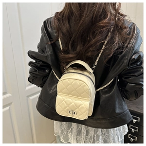 Detailopname van mini gewatteerde crossbodytas met zilveren ketting en crème PU-leder