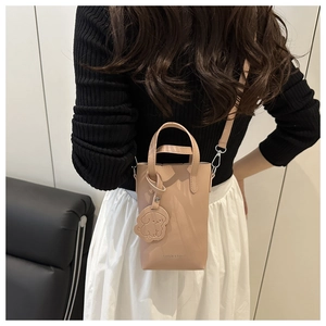 Detail of light pink mini square bag with leather dog charm and 'FASHION & BAGS' stamp