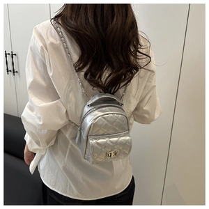 Silver quilted mini bag detail with metal chain strap and turn-lock closure on model