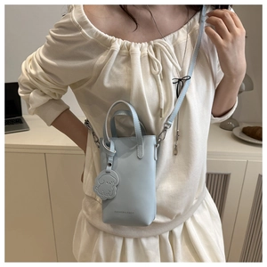 Close-up of mini light blue bucket bag with cute dog charm and fashion text detail