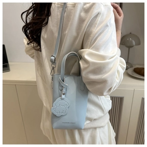 Detail of light blue crossbody phone bag with dog charm and Fashion & Bags text
