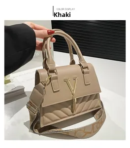 Detail of khaki leather handbag with gold V-logo, tassel charm and woven shoulder strap