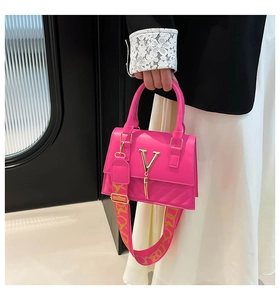 Detail of hot pink quilted bag featuring golden V-logo and wide patterned shoulder strap