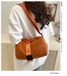 Detailed back view of a bright orange nylon crossbody bag with black buckle on wide strap