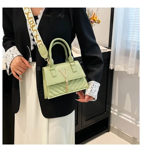 Close-up of pistachio green crossbody bag with gold V logo, fringe, and quilted leather