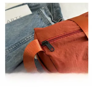 Detailed view of smooth black zipper closure and nylon handle on orange oxford shoulder bag