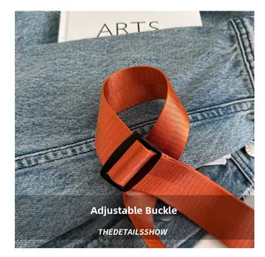 Detail of adjustable black buckle with high-density orange nylon strap on a crossbody bag