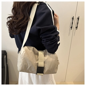 Close-up of beige Oxford crossbody bag with wide strap and black tactical buckle