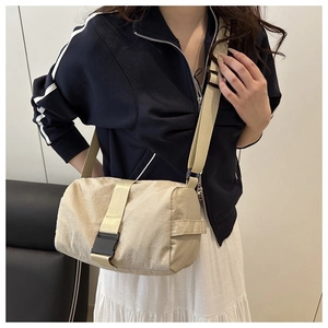 Detail view of beige nylon crossbody bag with black buckle and wide shoulder strap