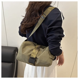 Olive green nylon crossbody bag showing the adjustable strap and buckle on the model