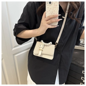 Detail of beige mini square crossbody bag with pearl handle and woven texture detail