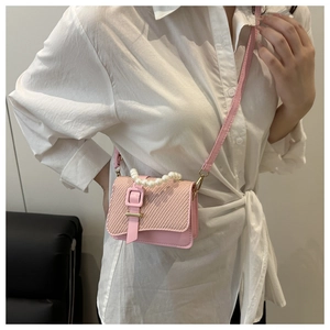 Detailed close-up of pink mini crossbody bag with woven flap and white pearl handle
