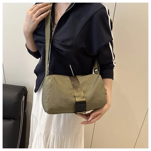 Detail of army green nylon crossbody bag with black plastic buckle and textured fabric