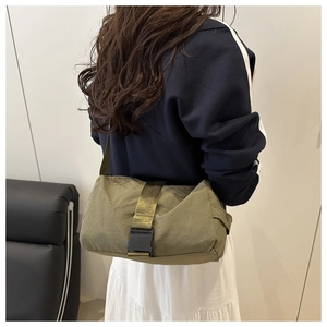 Détail du sac bandoulière en nylon vert olive avec boucle noire et sangle de transport