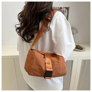 Detail of caramel nylon crossbody bag featuring adjustable strap and buckle closure