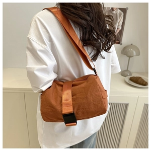 Detail of orange nylon crossbody bag with adjustable wide strap and black buckle closure