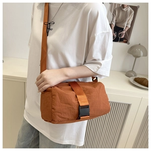 Detail of caramel nylon crossbody bag with wide strap and black buckle closure