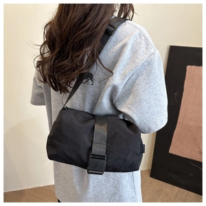 Vue latérale du sac bandoulière noir en nylon porté par un mannequin montrant sa capacité