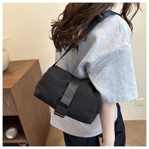 Detail of black nylon crossbody bag with buckle strap and smooth waterproof texture