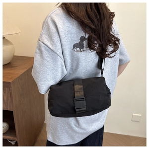 Rear view of black oxford crossbody bag with buckle detail on casual grey t-shirt