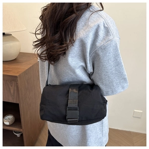 Minimalist black Oxford cloth crossbody bag with large plastic buckle on model