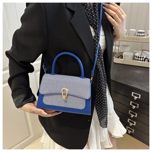 Detail of blue leather and striped fabric shoulder bag with a polished metal clasp