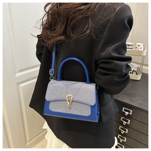 Blue crossbody bag with blue and white stripes detail on a model in a home setting