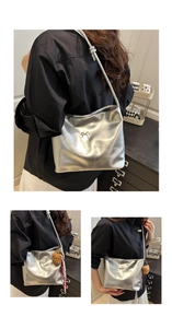 Details der silbernen Metallic-Umhängetasche mit Schleife und Plüschbär-Anhänger